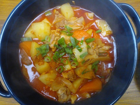 A steaming pot of spicy Korean chicken and potato stew, dakbokkeumtang